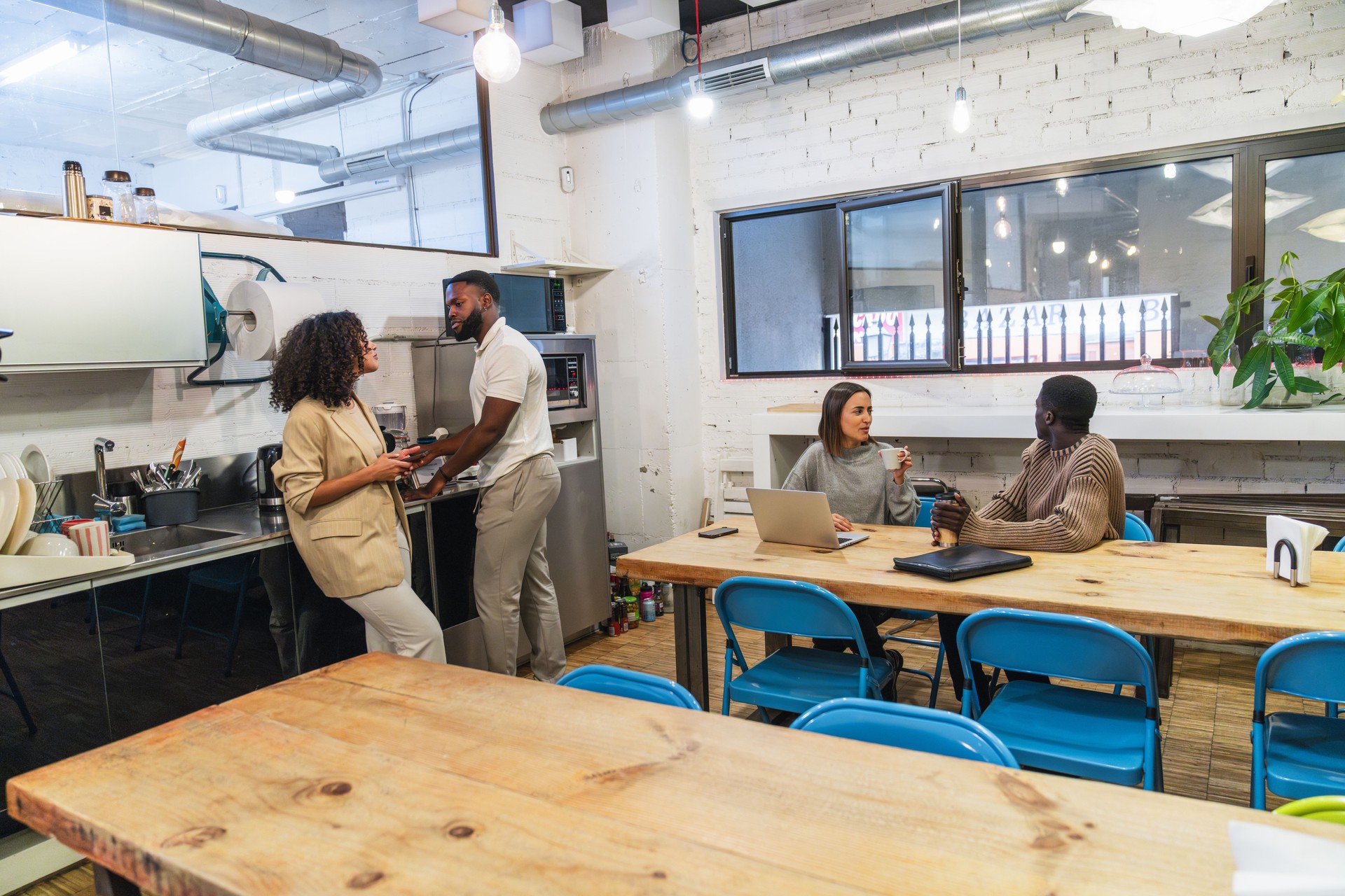 Multiethnic young adult businesspeople chatting during coffee break in coworking office space