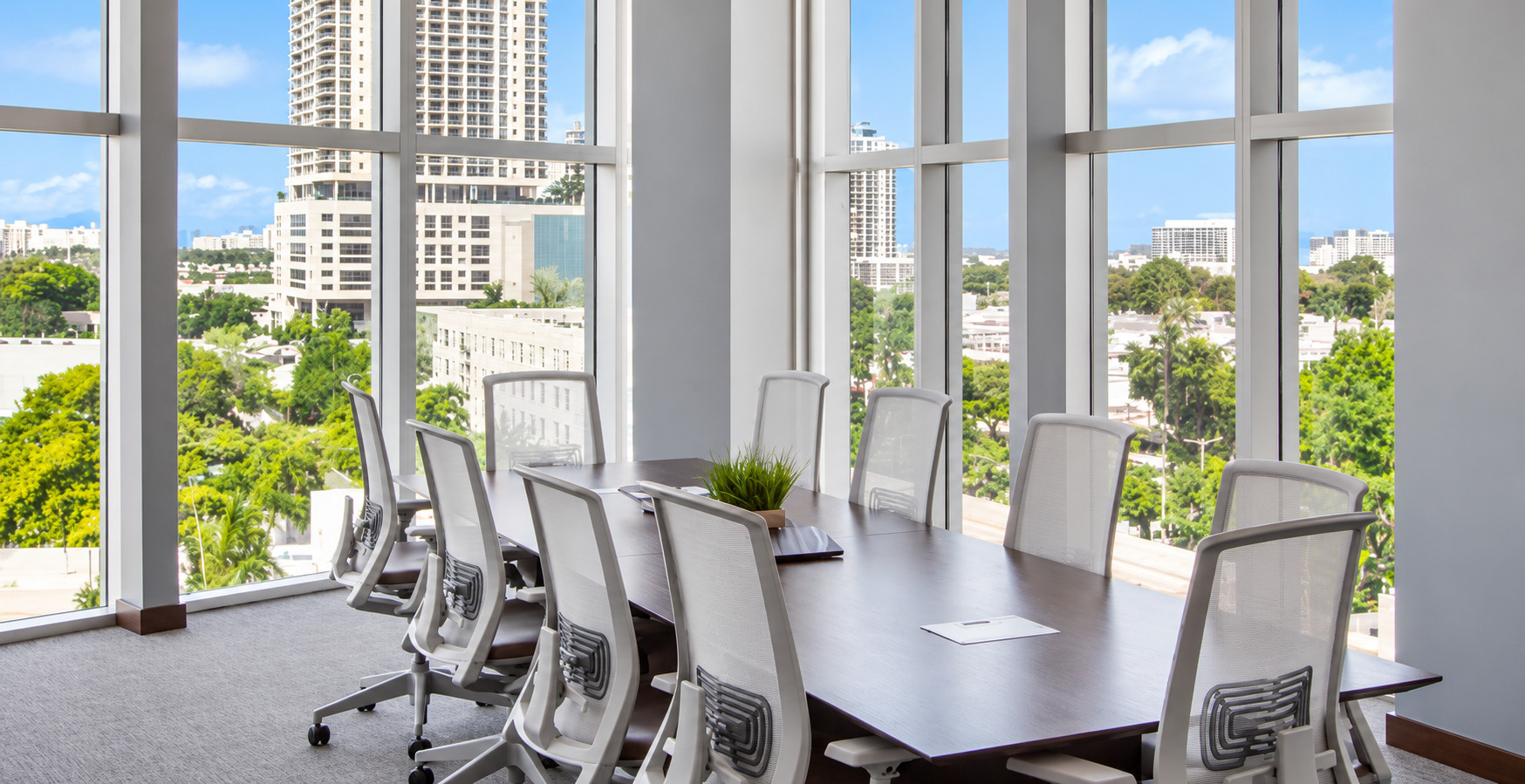 Bright conference room with floor-to-ceiling windows and Miami city views at The HUB